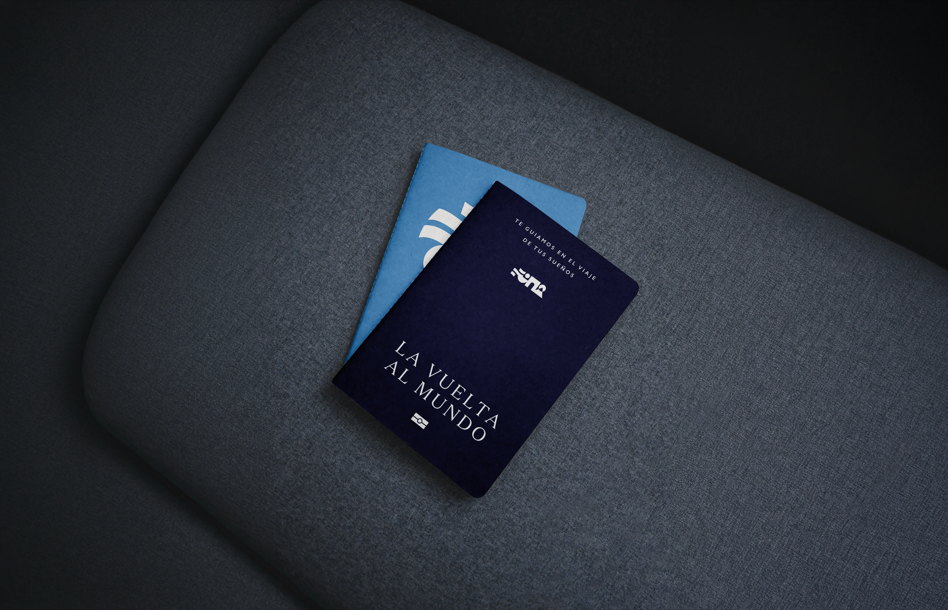 Dark blue La Vuelta al Mundo passports resting on a textured charcoal surface.