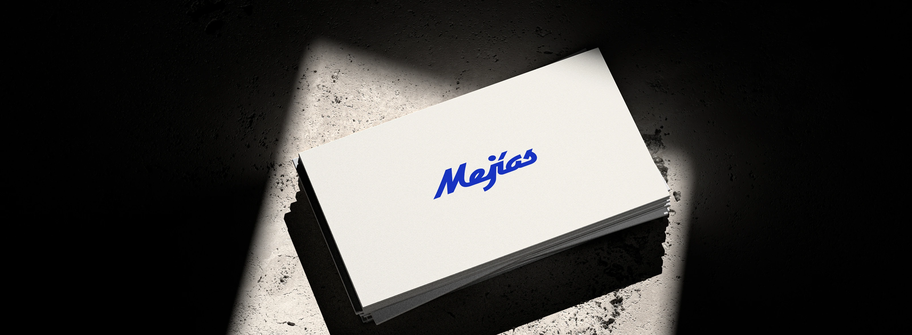A stack of Mejías business cards lit dramatically, featuring the blue script wordmark.