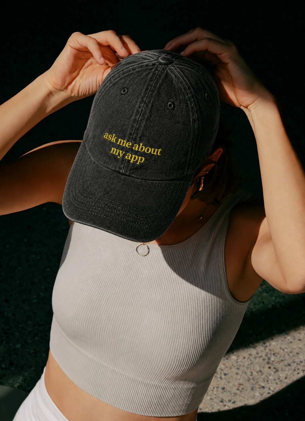 Person wearing a black Paddle cap embroidered with the phrase ask me about my app.