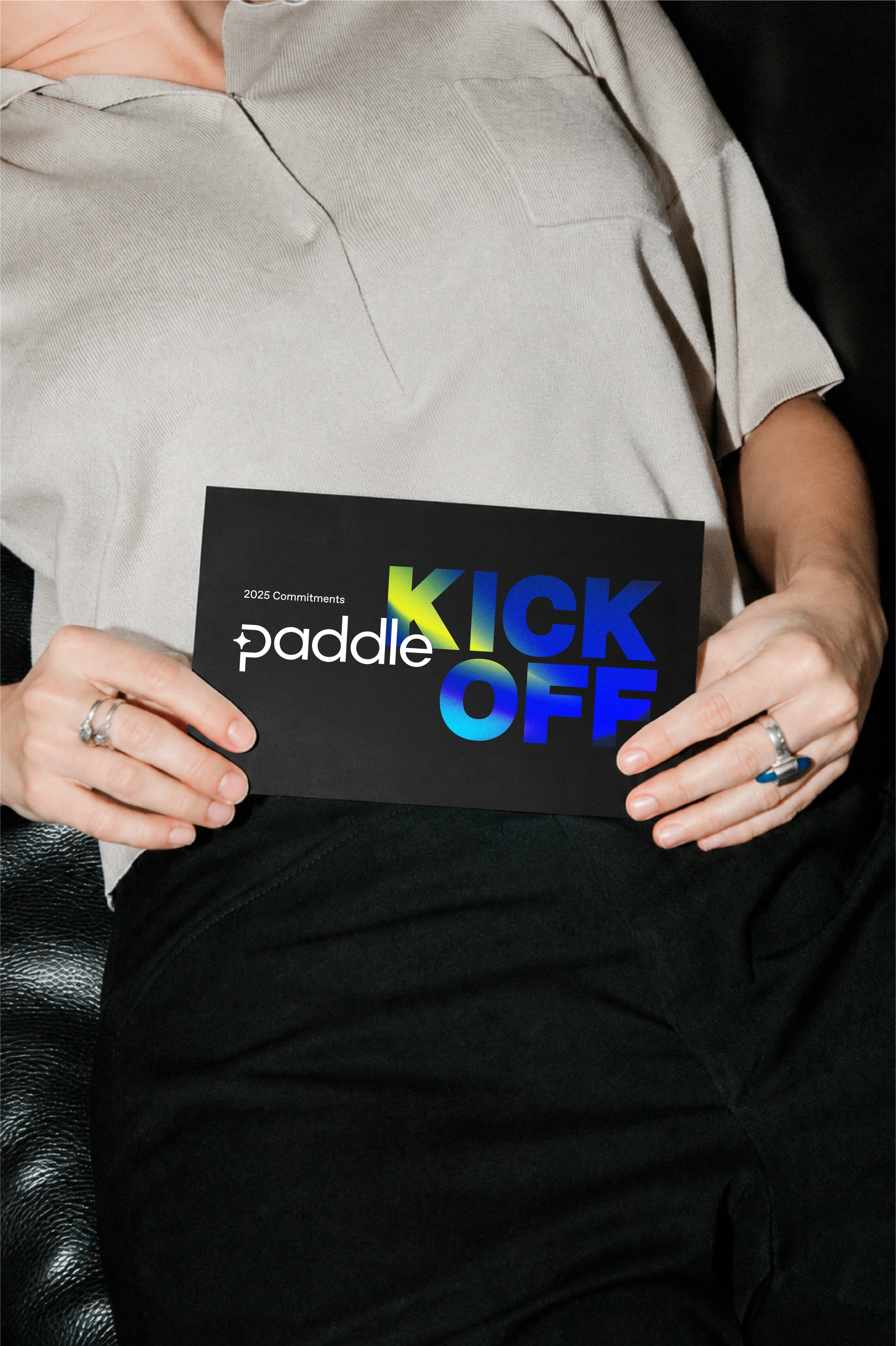 Person holding a black Paddle kickoff cue card with vivid blue and yellow lettering.