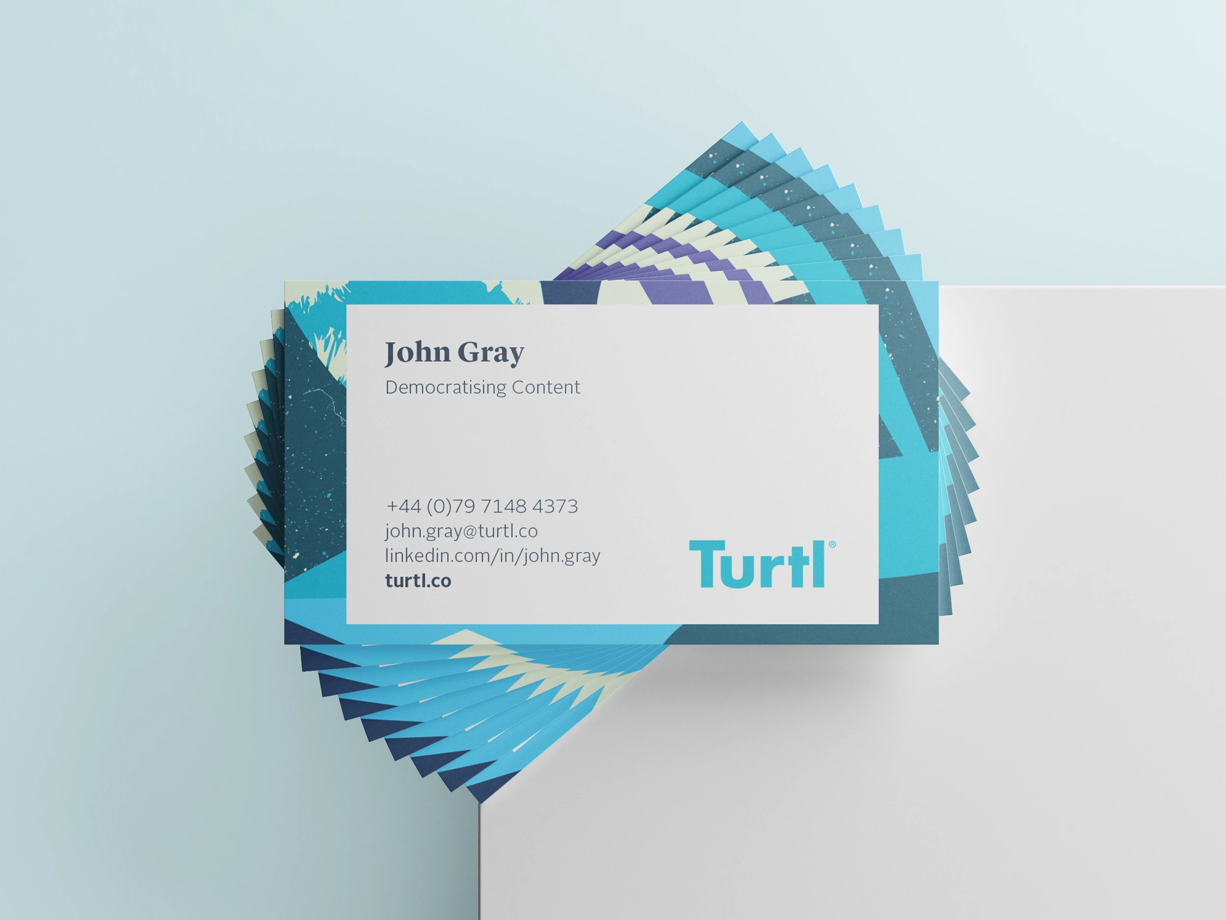 Turtl business cards arranged in a fan with a layered blue and green pattern.